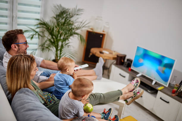 Young parents watching TV with baby boys.